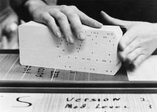Hands holding a stack of punched cards.
